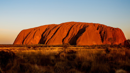A photo taken at day time of Uluru.